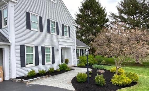 Modern home exterior with landscaped garden, paving stones, and decorative plants.